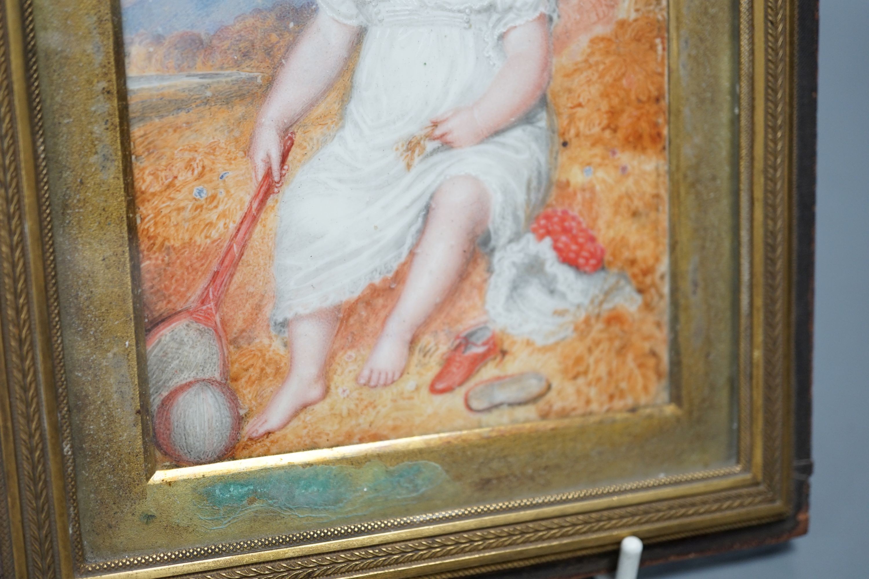 A 19th century portrait miniature on ivory of an infant, with racket and ball, 10 cms wide x 14 cms high.